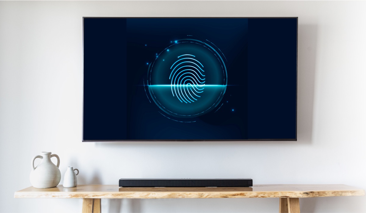 A hanging LG TV with an image of a fingerprint on the screen. Below the TV is a drawer with a soundbar on it