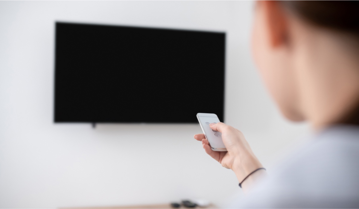 A person pointing a remote control at a TV
