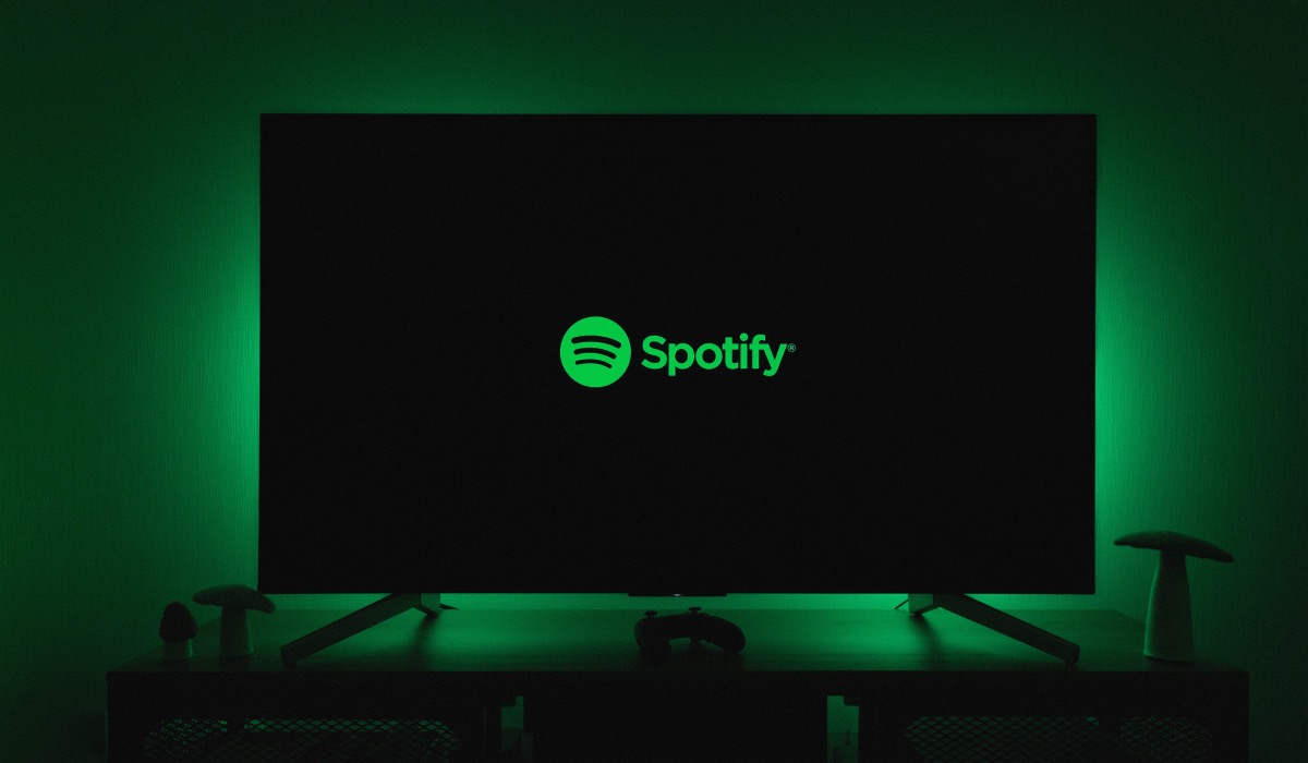Spotify logo on an LG Smart TV. The room is dark and the Tv is backlit with green neon light