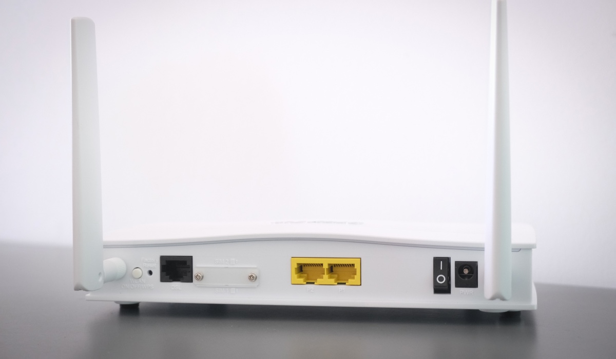 A router seen from the back. It has two antennas and some empty sockets for power and LAN cables