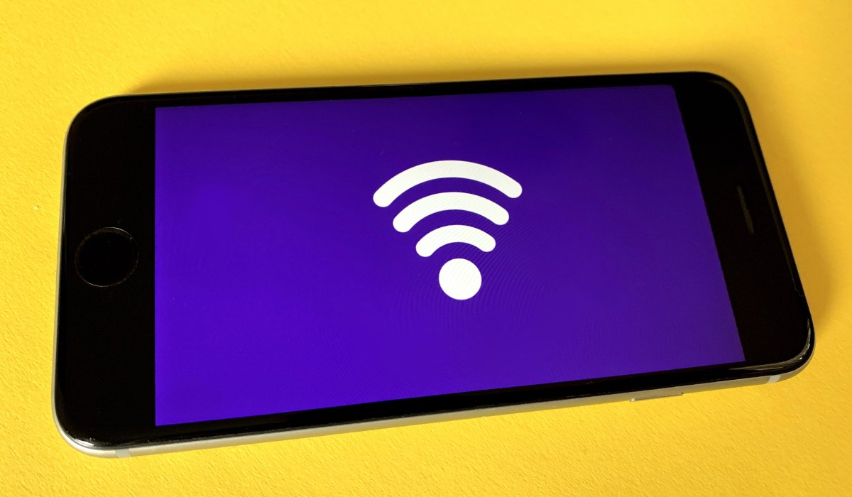 WiFi symbol on blue background on an iPhone. The iPhone is on a yellow surface