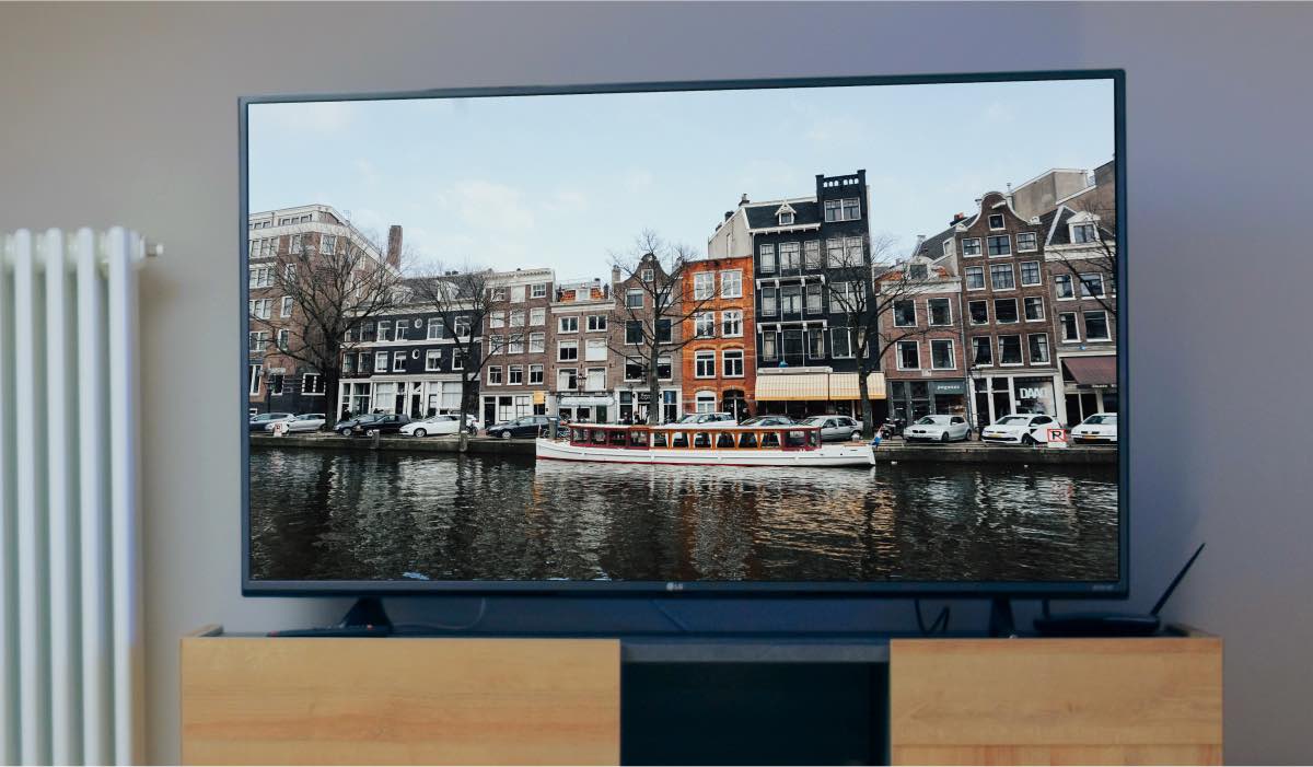 An LG Tv with a screensaver showing Amsterdam houses. There's a radiator next to the LG tV