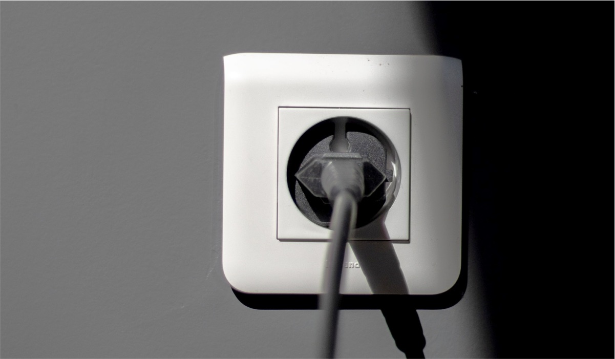 A white power socket with a grey power cable plugged in.