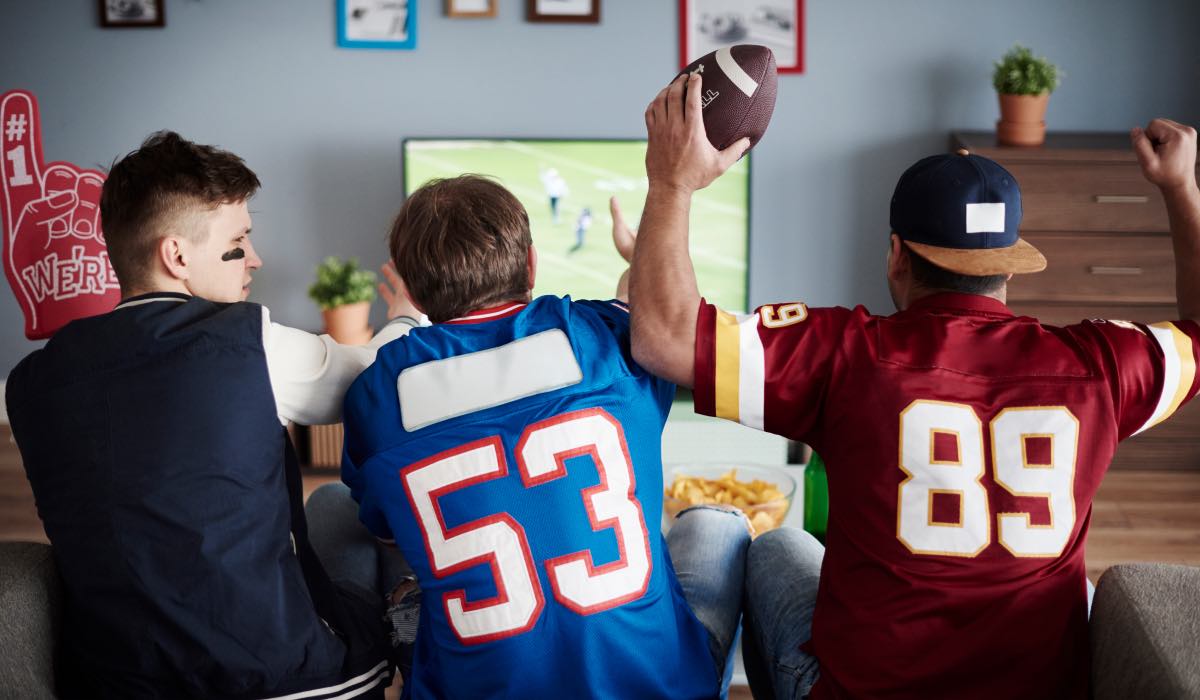 three men in player tshirts watch american football