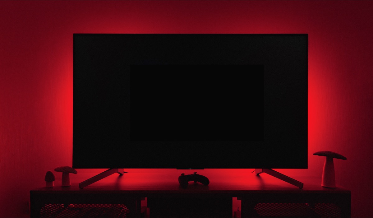 An LG Tv with a black screen in a dark room with red backlights