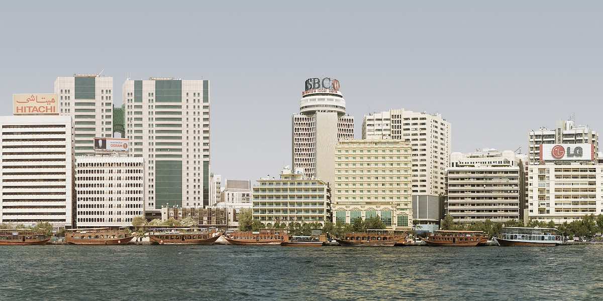 A city waterfront with office buildings. One of the buildings has LG logo, another HSBC logo and another Hitachi logo